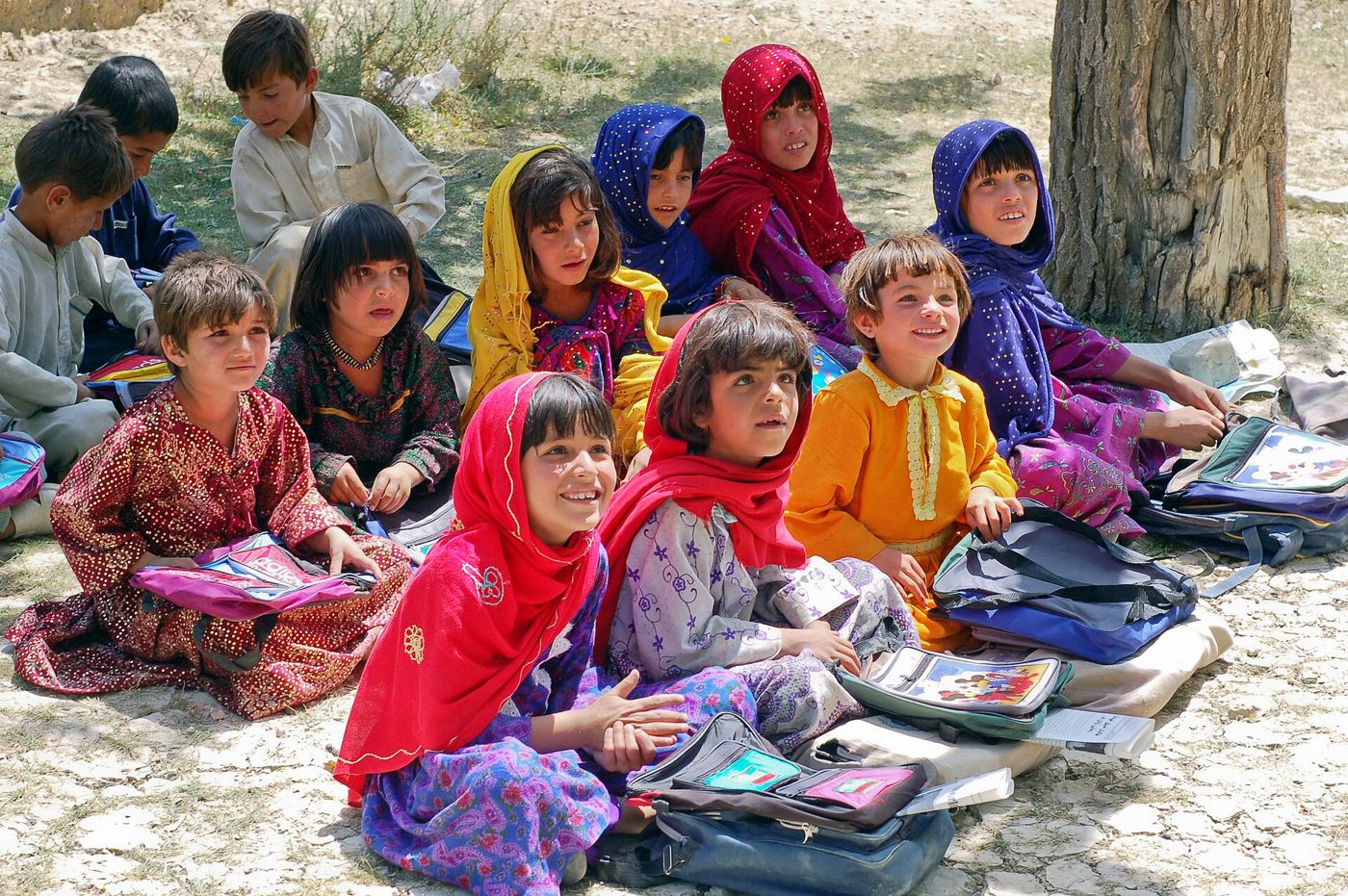 Des écolières afghanes assises dehors avec leurs cahiers